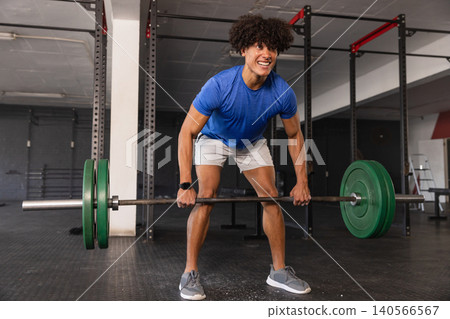 African american male lifting barbell with plates wearing sports watch in gym section 140566567