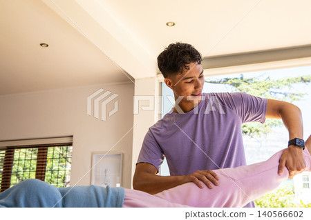 Asian male fitness trainer guiding client stretching leg in home wearing smartwatch, copy space Asian male fitness trainer guiding client stretching leg in home wearing smartwatch, copy space 140566602
