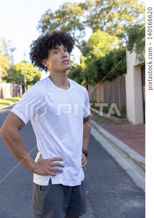 African american male runner pausing on suburban sidewalk African american male runner pausing on suburban sidewalk 140566620