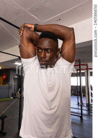 African American man checking fitness tracker on wrist standing by squat rack in fitness center African American man checking fitness tracker on wrist standing by squat rack in fitness center 140566650