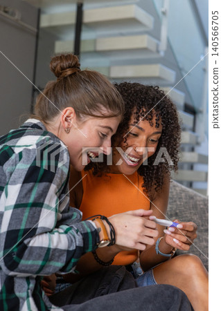 Female couple examining pregnancy test while leaning forward on living room sofa Female couple examining pregnancy test while leaning forward on living room sofa 140566705