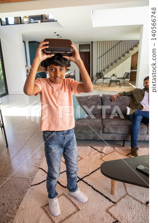Indian father and son playing with virtual reality headset in living room on patterned rug Indian father and son playing with virtual reality headset in living room on patterned rug 140566748