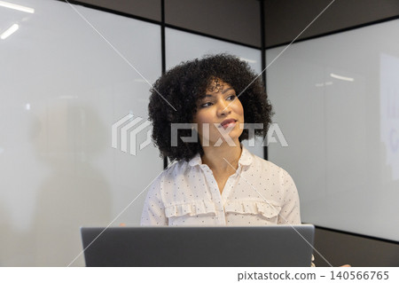 African american woman working on laptop in meeting room with whiteboard walls, chart projection African american woman working on laptop in meeting room with whiteboard walls, chart projection 140566765