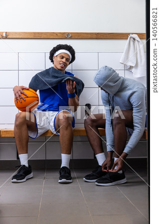 African american male basketball players sitting in room, checking smartphone, copy space African american male basketball players sitting in room, checking smartphone, copy space 140566821