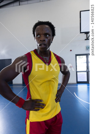 African american man standing on blue court in sports hall wearing uniform by scoreboard African american man standing on blue court in sports hall wearing uniform by scoreboard 140566825