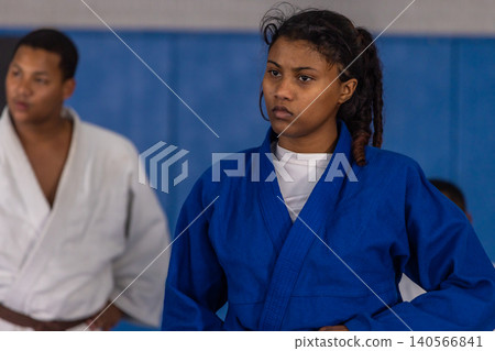 African american partners practicing judo in gym with blue white gis brown belt near padded wall African american partners practicing judo in gym with blue white gis brown belt near padded wall 140566841