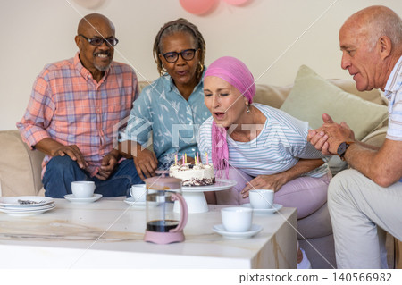 Diverse senior friends celebrating birthday in living room with cake, coffee cups, french press Diverse senior friends celebrating birthday in living room with cake, coffee cups, french press 140566982
