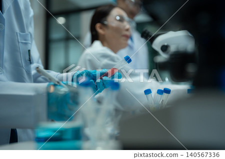 Team Asian environmental scientists analyzing water quality samples with centrifuge and petri dish in laboratory. Team Asian environmental scientists analyzing water quality samples with centrifuge and petri dish in laboratory. 140567336