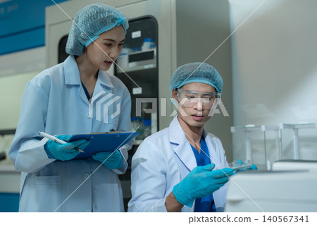 Team Asian environmental scientists analyzing water quality samples with centrifuge and petri dish in laboratory. Team Asian environmental scientists analyzing water quality samples with centrifuge and petri dish in laboratory. 140567341