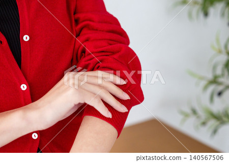 A woman's hands rolling up the sleeves of her red cardigan. A woman's hands rolling up the sleeves of her red cardigan. 140567506