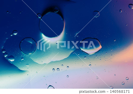 Macro shot of fluid dynamics showing floating oil drops over vibrant, colorful light leaks Macro shot of fluid dynamics showing floating oil drops over vibrant, colorful light leaks 140568171