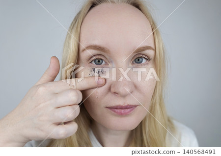 Woman demonstrating easy tubing mascara removal process using warm water. Woman washing off innovative thermal cosmetics that slides off eyelashes in tubes without smudging Woman demonstrating easy tubing mascara removal process using warm water. Woman washing off innovative thermal cosmetics that slides off eyelashes in tubes without smudging 140568491