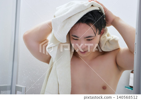 一名二十多歲的男子正在用浴巾擦頭。 一名二十多歲的男子正在用浴巾擦頭。 140568512