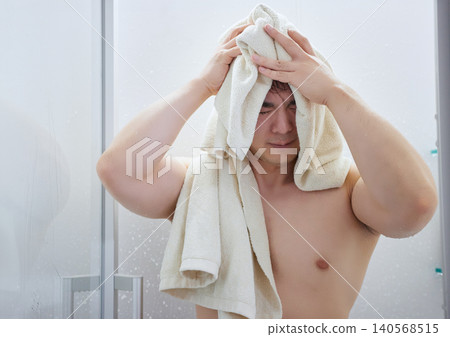 A man in his 20s wiping his head with a bath towel. A man in his 20s wiping his head with a bath towel. 140568515