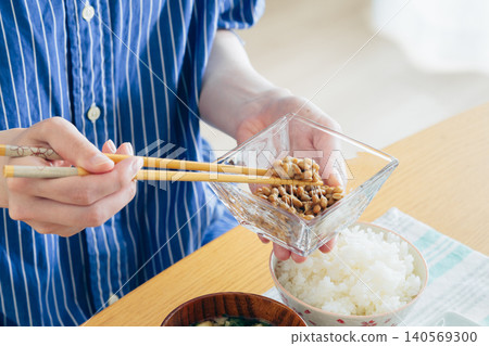 A young woman's hands as she eats natto 140569300