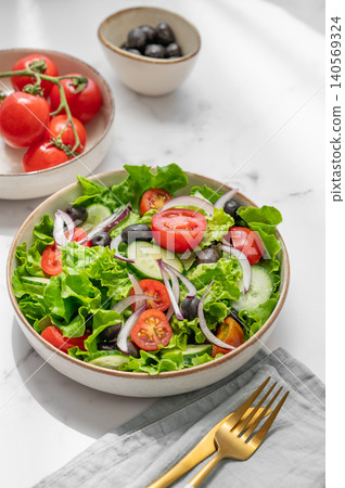 A fresh salad of tomatoes, cucumbers, lettuce, red onions, and olives on a marble background A fresh salad of tomatoes, cucumbers, lettuce, red onions, and olives on a marble background 140569324