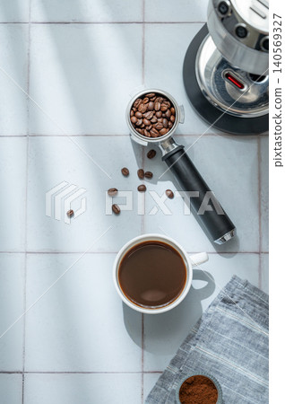 A flat lay of a cup of black coffee, a portafilter with roasted beans, ground coffee A flat lay of a cup of black coffee, a portafilter with roasted beans, ground coffee 140569327