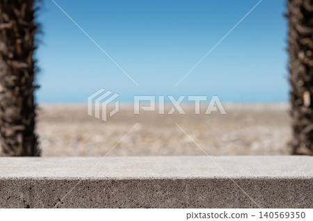 Concrete table surface with blurred palm trees, sea and beach on background. Concrete table surface with blurred palm trees, sea and beach on background. 140569350