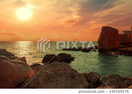 Rocky coast in the evening. The ruins of the ancient city. Sunset over the sea Rocky coast in the evening. The ruins of the ancient city. Sunset over the sea 140569576