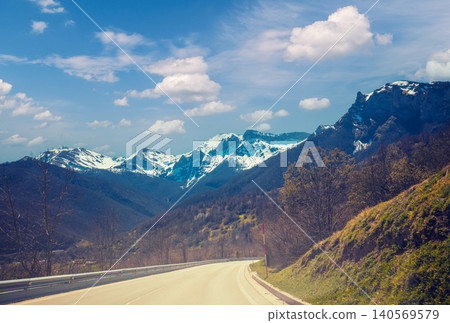 View of beautiful mountain landscape through the windscreen on a sunny day. Driving a car on mountain winding road in National park Picos de Europa. Cantabria, Spain, Europe View of beautiful mountain landscape through the windscreen on a sunny day. Driving a car on mountain winding road in National park Picos de Europa. Cantabria, Spain, Europe 140569579