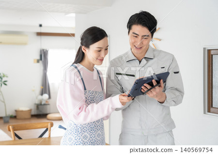 A housewife and a construction worker discussing renovation plans. A housewife and a construction worker discussing renovation plans. 140569754