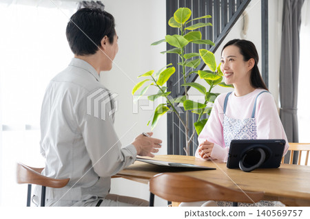 A housewife and a construction worker discussing renovation plans. A housewife and a construction worker discussing renovation plans. 140569757