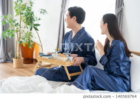 A middle-aged couple relaxing in their bedroom. A middle-aged couple relaxing in their bedroom. 140569764