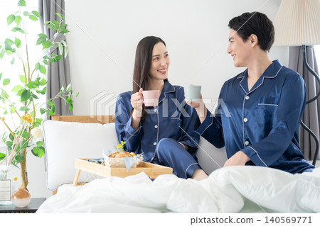 A middle-aged couple relaxing in their bedroom. A middle-aged couple relaxing in their bedroom. 140569771