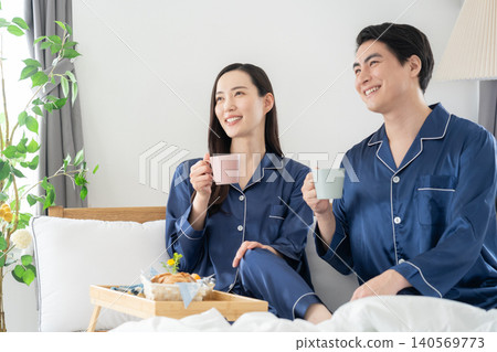 A middle-aged couple relaxing in their bedroom. A middle-aged couple relaxing in their bedroom. 140569773