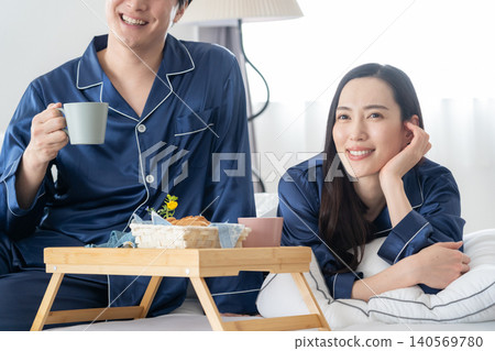 A middle-aged couple relaxing in their bedroom. A middle-aged couple relaxing in their bedroom. 140569780