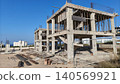 Unfinished concrete building under construction with exposed columns, scaffolding, and reinforcement bars, symbolizing urban development, engineering, and real estate growth. 140569921