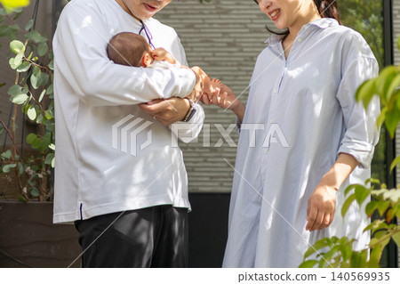 A young couple came out the front door with their newborn baby in their arms. A young couple came out the front door with their newborn baby in their arms. 140569935