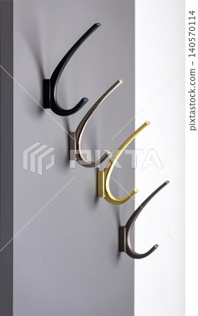 Metal hooks are displayed on a grey wall in a modern interior setting during the daytime Metal hooks are displayed on a grey wall in a modern interior setting during the daytime 140570114