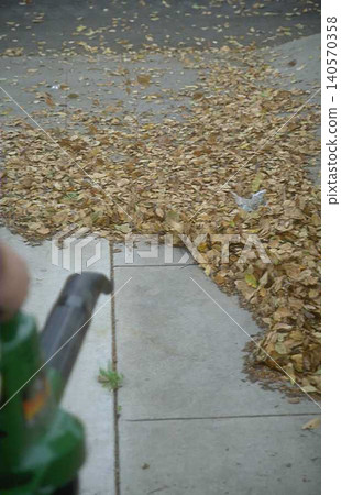 a Person Operating Green Leaf Blower on Concrete Surface 140570358