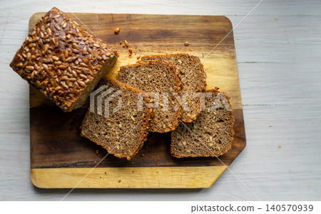 Sliced whole grain loaf with sunflower seeds on wooden cutting board overhead view Sliced whole grain loaf with sunflower seeds on wooden cutting board overhead view 140570939