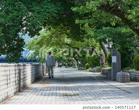 A senior man strolling along the Kiso River promenade in Inuyama City, a popular tourist destination, on a morning in early summer. A senior man strolling along the Kiso River promenade in Inuyama City, a popular tourist destination, on a morning in early summer. 140571127