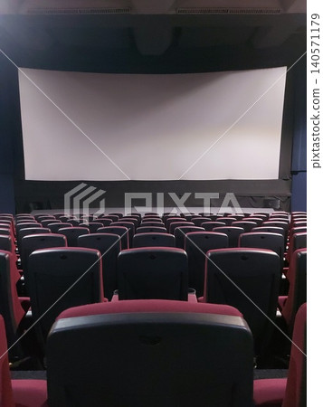 An empty cinema before a movie screening. White screen in front of empty cinema seats.  140571179