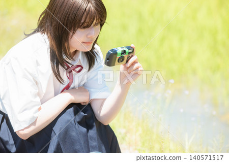 A high school girl looking through a film camera A high school girl looking through a film camera 140571517
