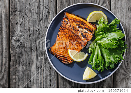 Baked salmon entree with lemon on a plate 140571634