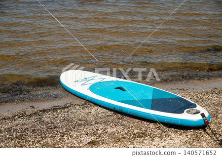 Stand up paddle board on the shore by the water during sunny weather 140571652