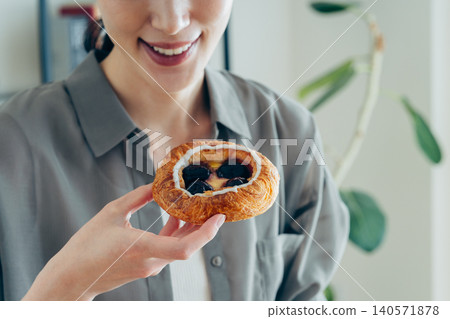 一位年輕女子正在吃一塊黑櫻桃丹麥酥。 140571878