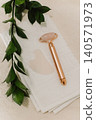 Facial rose quartz stone massage roller and gua sha massager on a white towel background. 140571973