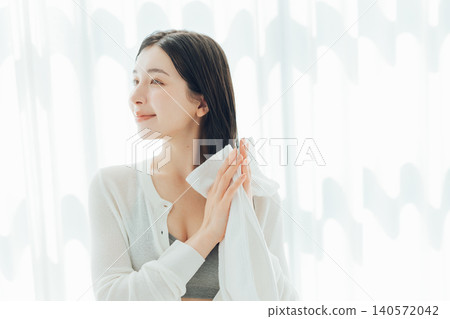 Young woman wiping her wet hair with a towel Young woman wiping her wet hair with a towel 140572042