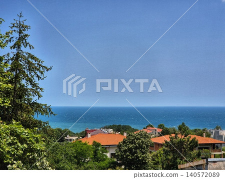 view of the beautiful seascape. roofs of houses are buried in greenery and the sea view of the beautiful seascape. roofs of houses are buried in greenery and the sea 140572089