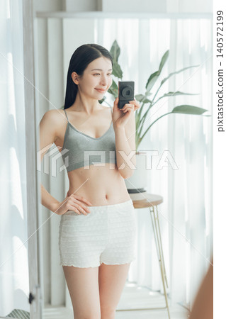 A woman takes a selfie in the mirror, showing off her toned body. 140572199