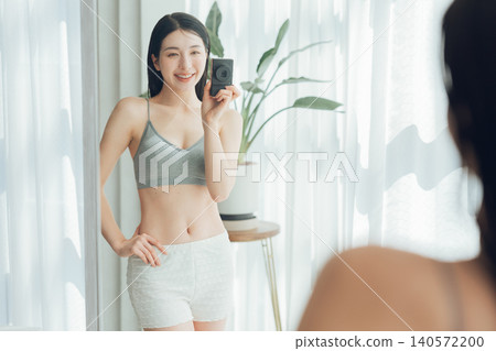 一名女子對著鏡子自拍,展現她健美的身材。 一名女子對著鏡子自拍,展現她健美的身材。 140572200