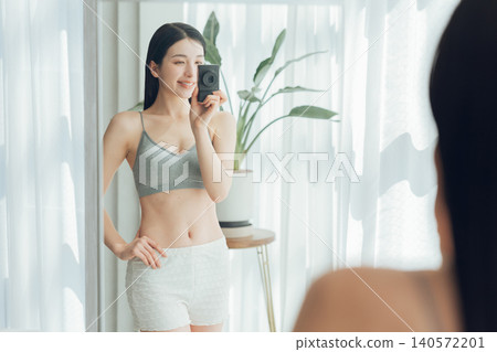 一名女子對著鏡子自拍,展現她健美的身材。 一名女子對著鏡子自拍,展現她健美的身材。 140572201