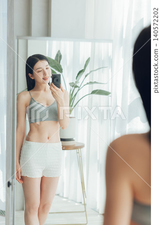 A woman takes a selfie in the mirror, showing off her toned body. A woman takes a selfie in the mirror, showing off her toned body. 140572202
