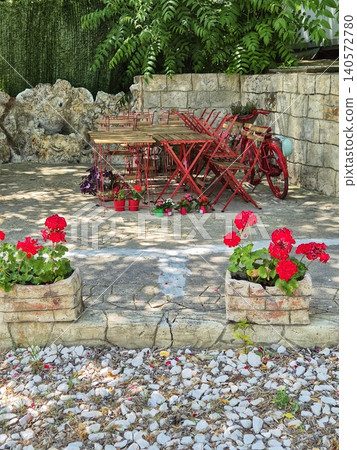 cozy cafe before opening on the coast. red flowers in flowerbeds and wooden tables. interesting design cozy cafe before opening on the coast. red flowers in flowerbeds and wooden tables. interesting design 140572780