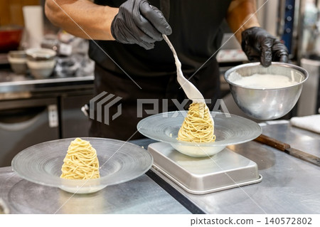 糕點師完成蒙布朗蛋糕製作時的雙手。 糕點師完成蒙布朗蛋糕製作時的雙手。 140572802